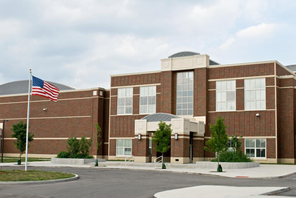 Outside view of the entrance of a school building, with a the American flag pole on the left. 